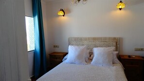 A neatly made bed with white linens, two bedside tables, a patterned headboard, and two wall-mounted lamps. - Hotel Casa Día y Noche (Calpe)