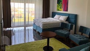 A modern bedroom with a large bed, a blue headboard, a small round table, and matching armchairs. - White Tower Mamaia (Navodari)