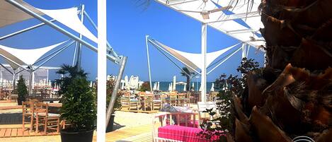 An outdoor seating area with tables and chairs, umbrellas, and potted plants.