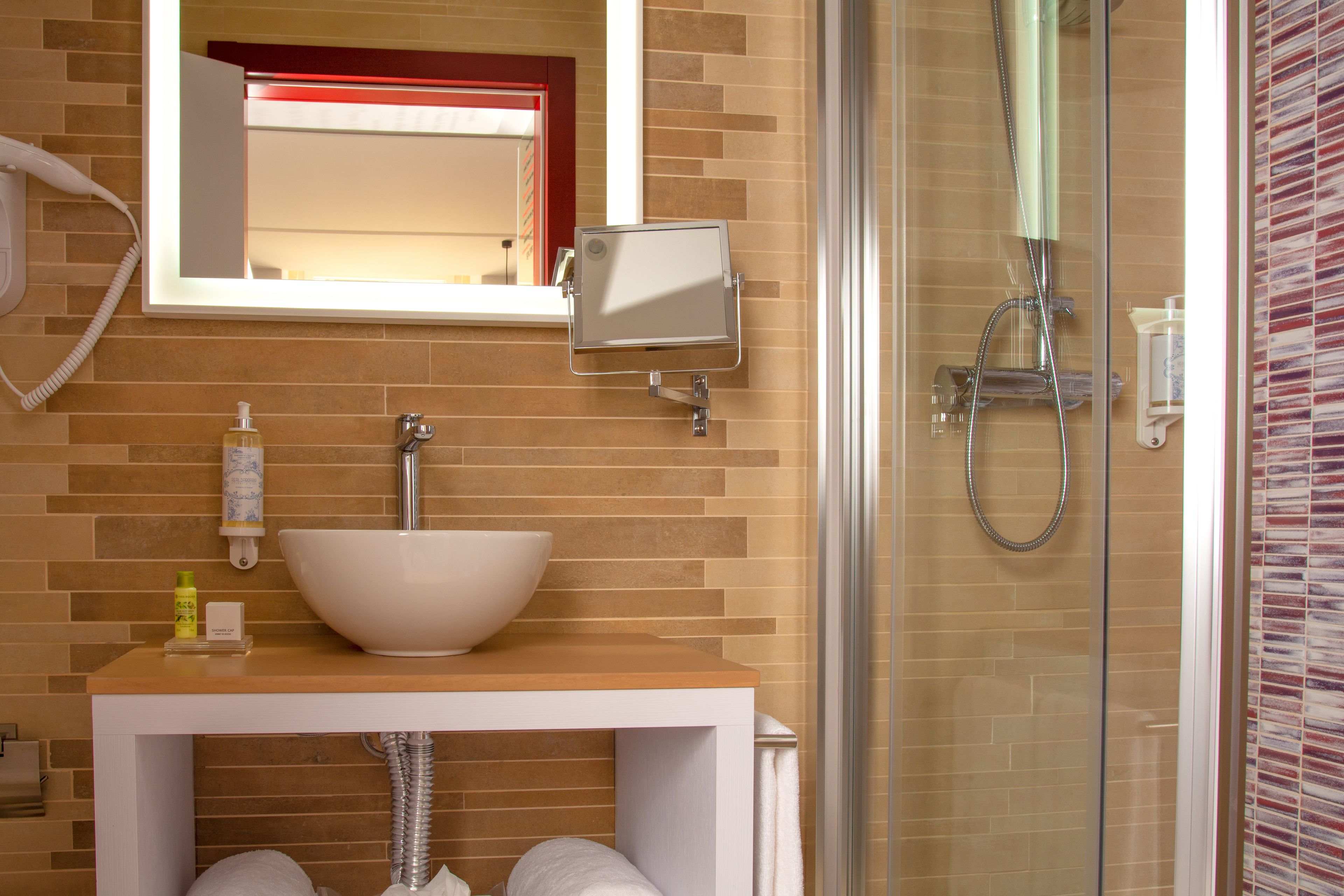Ein Badezimmer mit einem weißen Waschbecken, einem Spiegel und einer Duschkabine aus Glas.