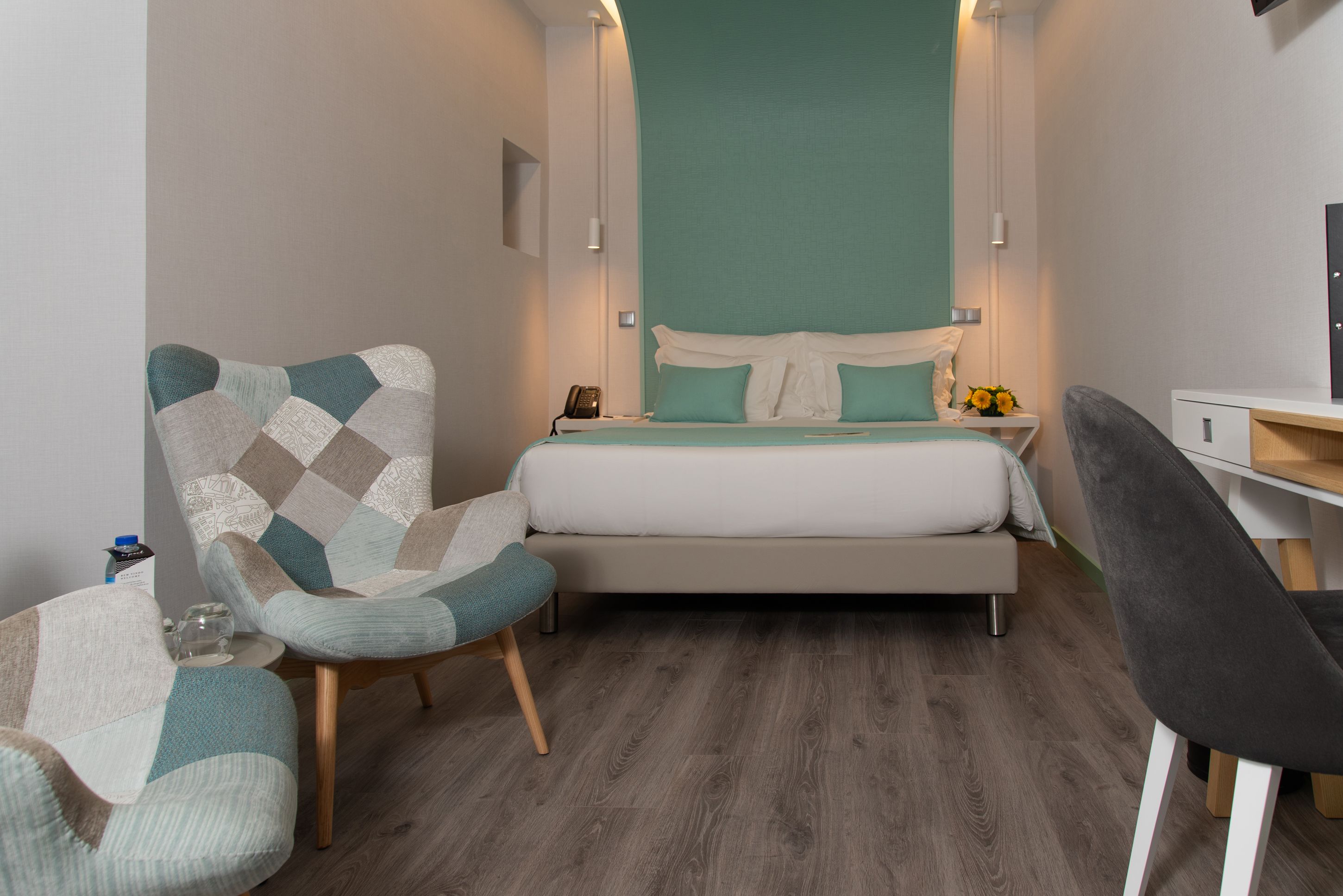 A modern bedroom with a bed, a chair, a desk, and a nightstand.