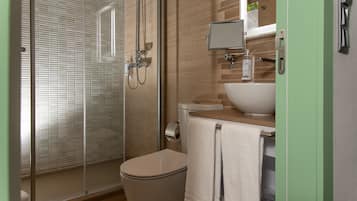 A modern bathroom with a glass-enclosed shower, a toilet, a sink, and a mirror.