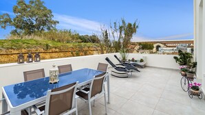 Una terrazza sul tetto con tavolo, sedie e piante in vaso.