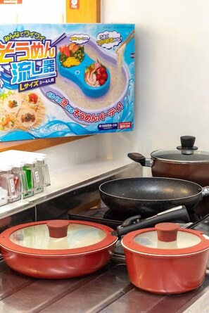 A kitchen with a cooking pot, a frying pan, and a red pot on the counter. - nuchigusui house (Motobu)