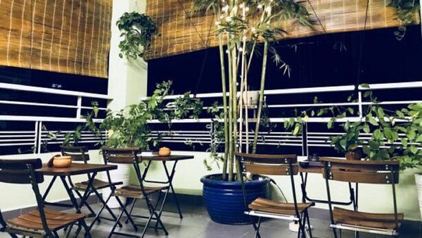 Una habitación con techo alto, persianas de bambú y varias mesas y sillas.