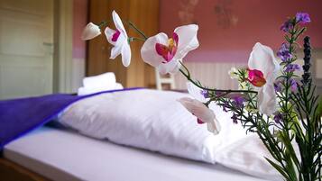 Un dormitorio con una cama, almohadas y un jarrón de flores.