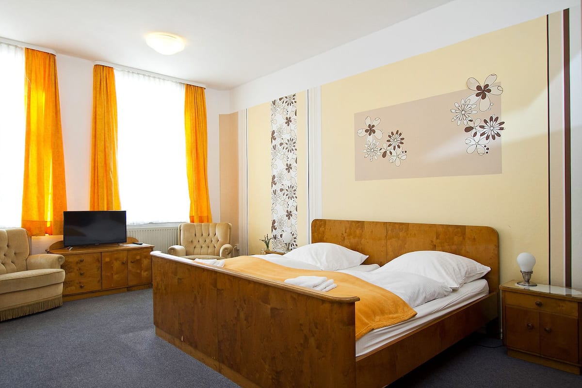 A hotel room with a wooden bed, a TV, a chair, and a nightstand.