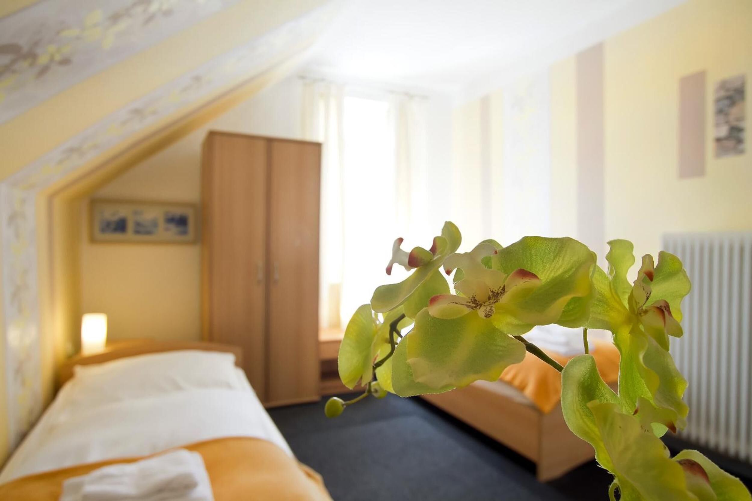 Une chambre d’hôtel avec un lit, une armoire en bois et une fenêtre avec des rideaux.