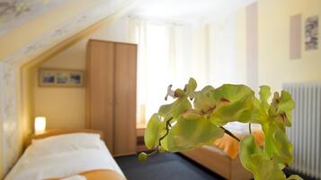 Une chambre d’hôtel avec un lit, une armoire en bois et une fenêtre avec des rideaux.