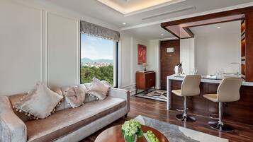 A modern living room with a sofa, a dining area with bar stools, and a view of the city.