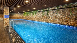 Una piscina interior con pared de piedra y mosaicos azules.