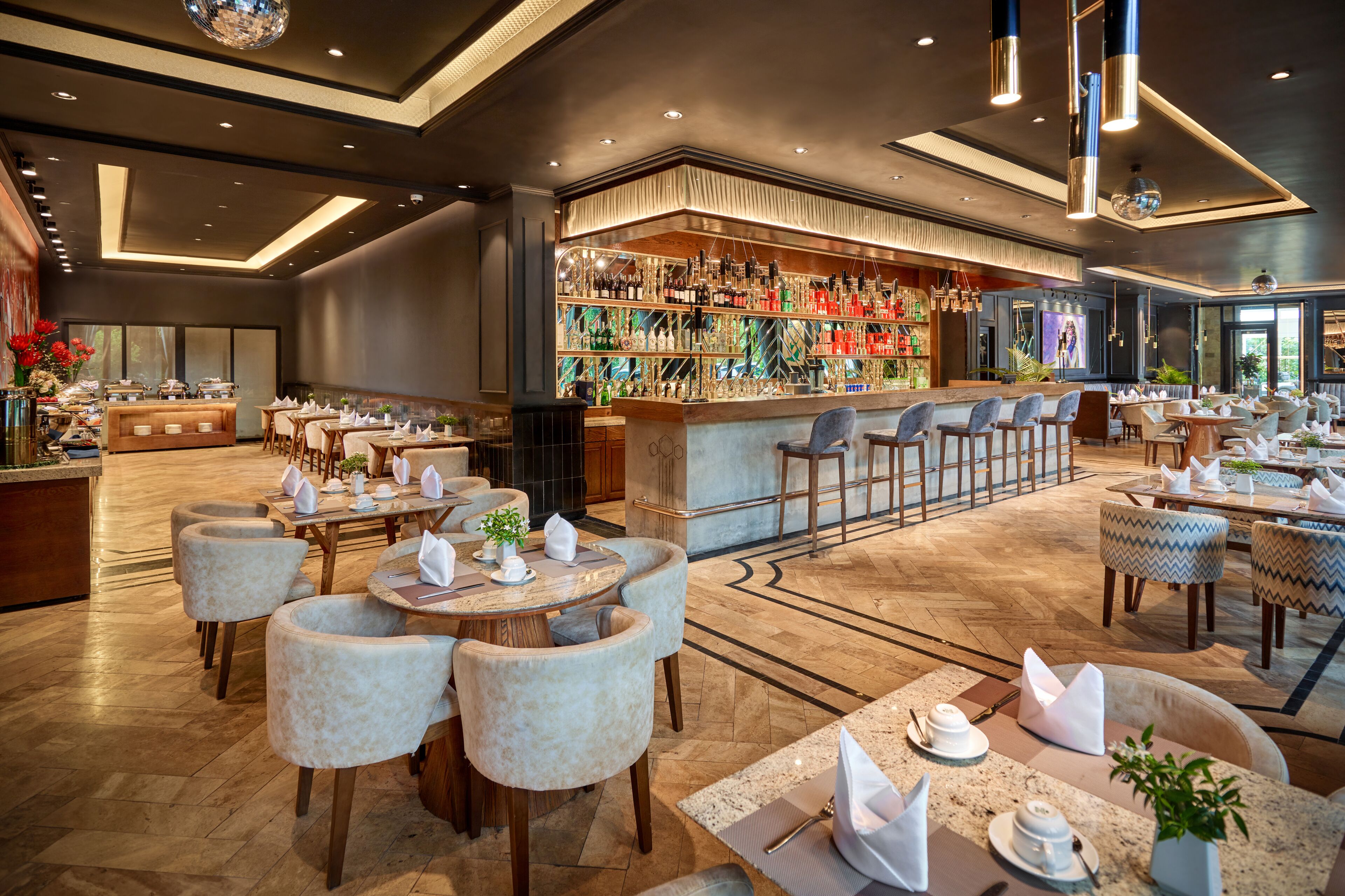 Een ruime hotellobby met een bar, diverse zithoeken en een modern design.