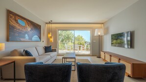 A modern living room with a sofa, two armchairs, a coffee table, a TV, and a painting. - Hapimag Resort Albufeira (Albufeira)