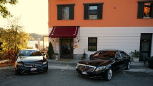 Deux voitures garées devant un immeuble surmonté d’un auvent rouge.
