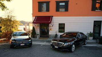 Two parked cars in front of a building with a red awning.