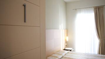 A hotel room with a bed, a nightstand, a lamp, and a window with curtains.