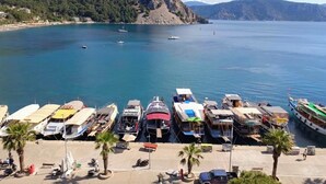 A marina with boats docked, a sandy beach, and a mountainous backdrop. - Es Apartments (Marmaris)