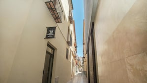 A narrow alleyway with buildings on either side, a sign for 'Soho Boutique Martyrs', and a clear blue sky above. - Feelathome Mártires Apartments (Málaga)