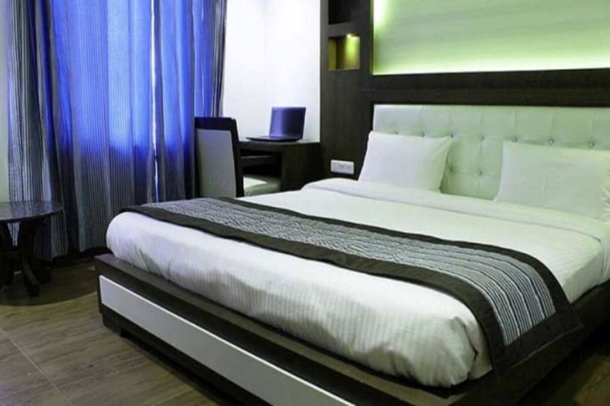 A hotel room with a large bed, a desk, and a chair.