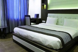 A hotel room with a large bed, a desk, and a chair.
