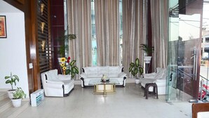 Un salon spacieux avec un ensemble de canapés blancs, une table basse en verre et des plantes en pot.