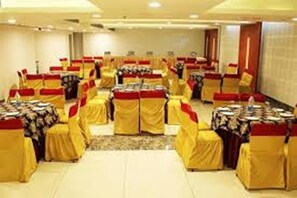 A conference room with rows of tables and chairs, each covered with yellow and red tablecloths.