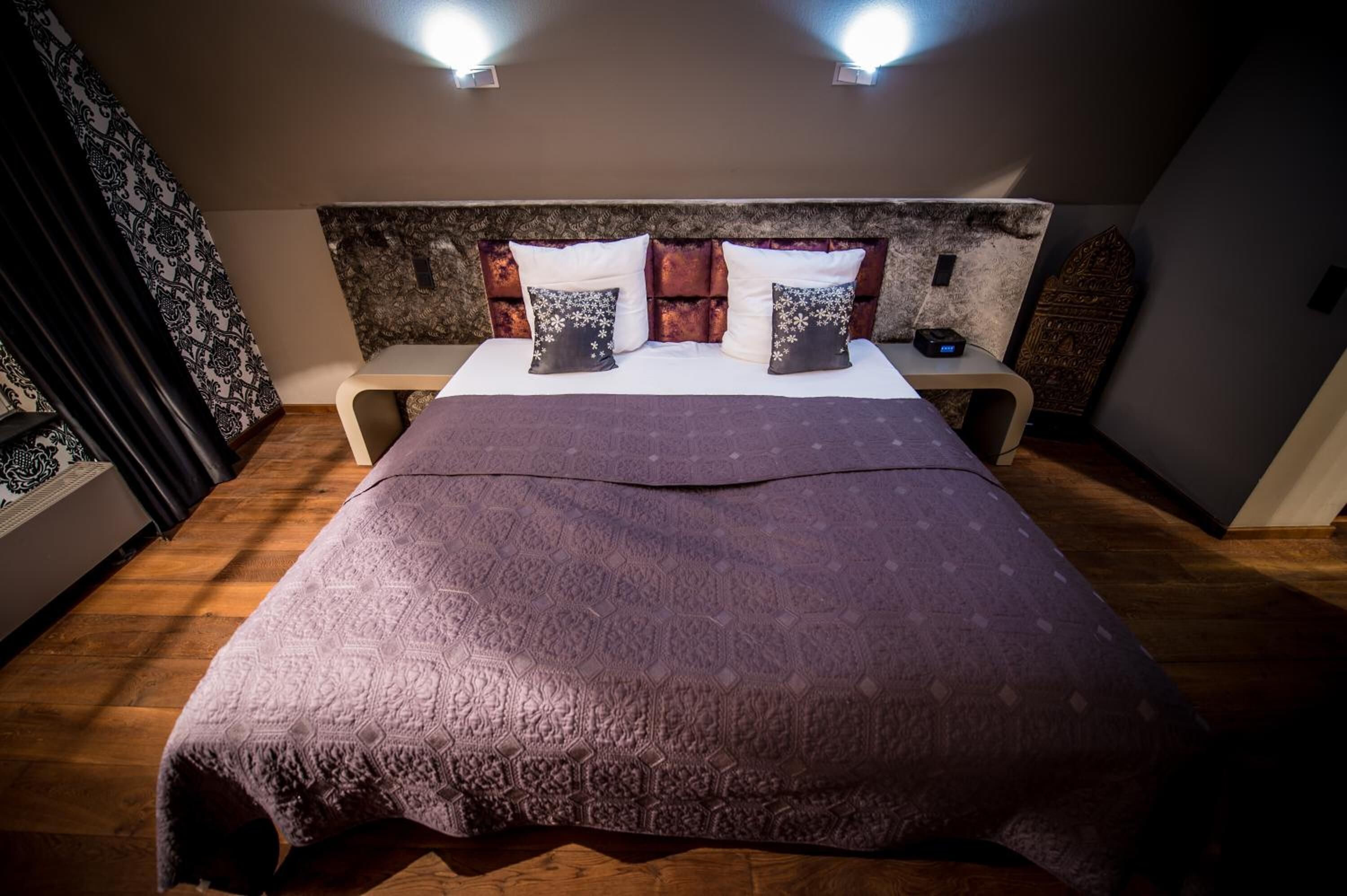 Une chambre à coucher avec un grand lit, une tête de lit à motifs et deux lampes de chevet.