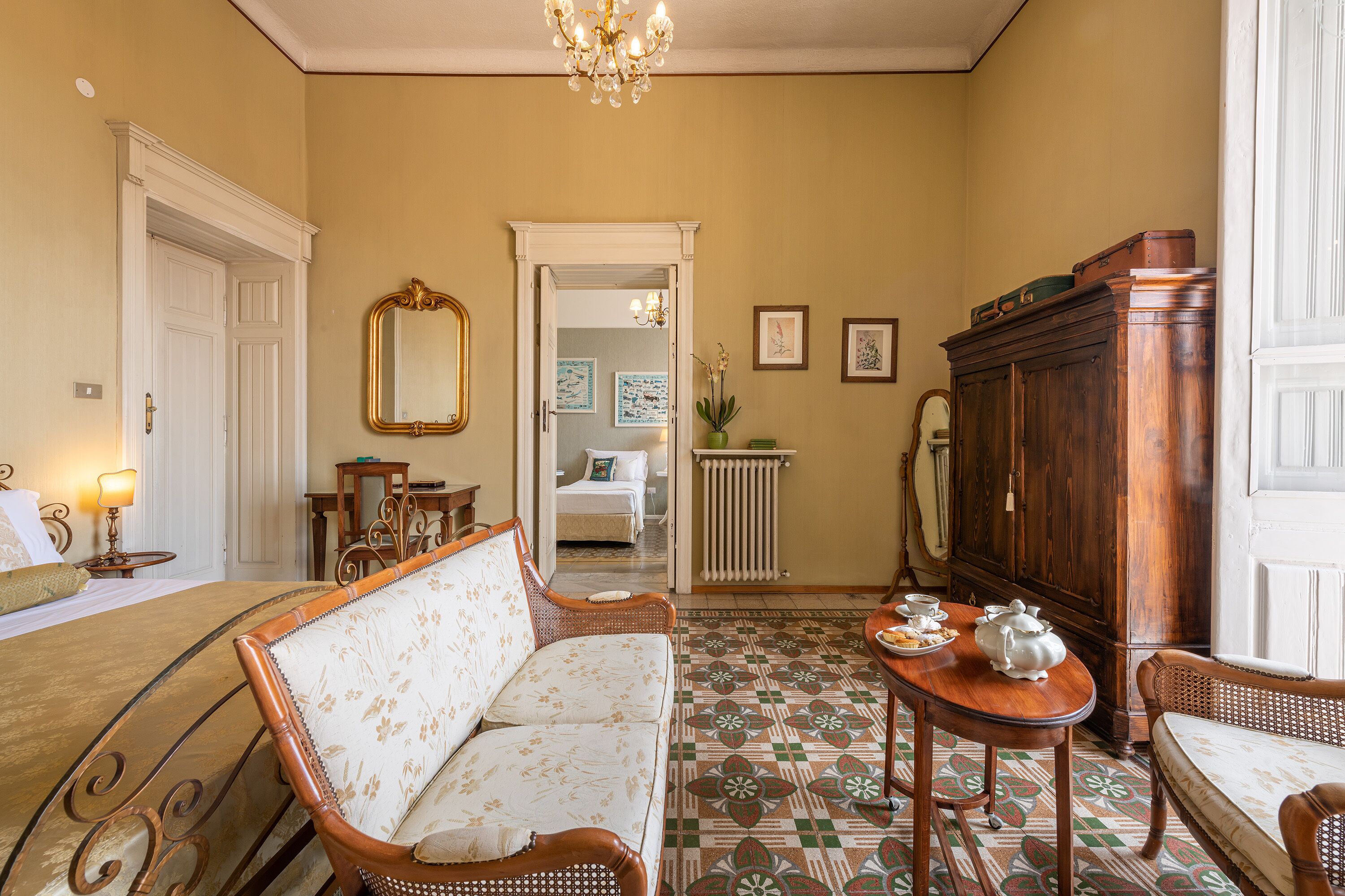 Quarto com sofá, mesa com bules, espelho e armário.