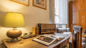 A wooden desk with a lamp, books, a radio, and a chair.