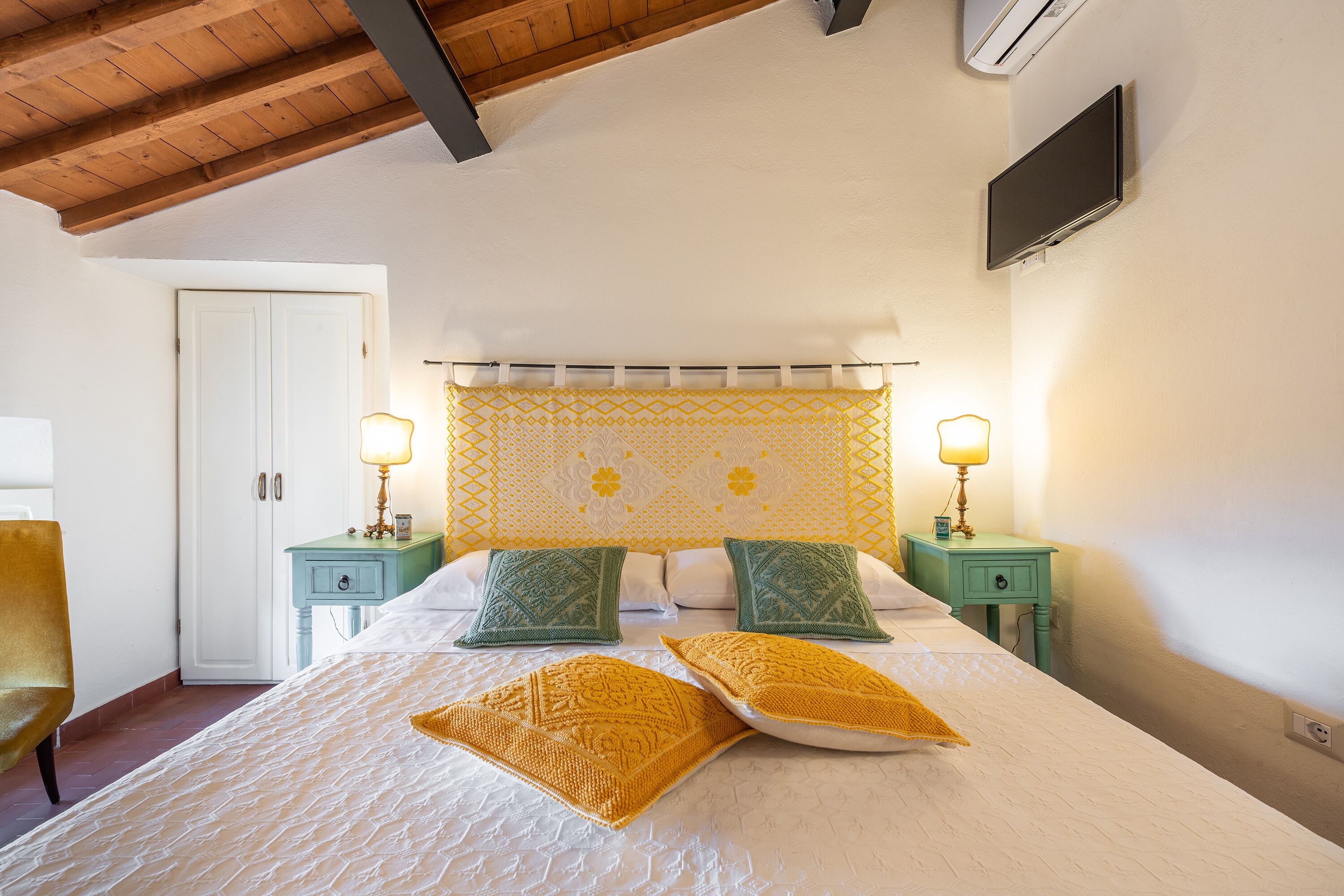 A bedroom with a bed, two nightstands, a TV, and a door.