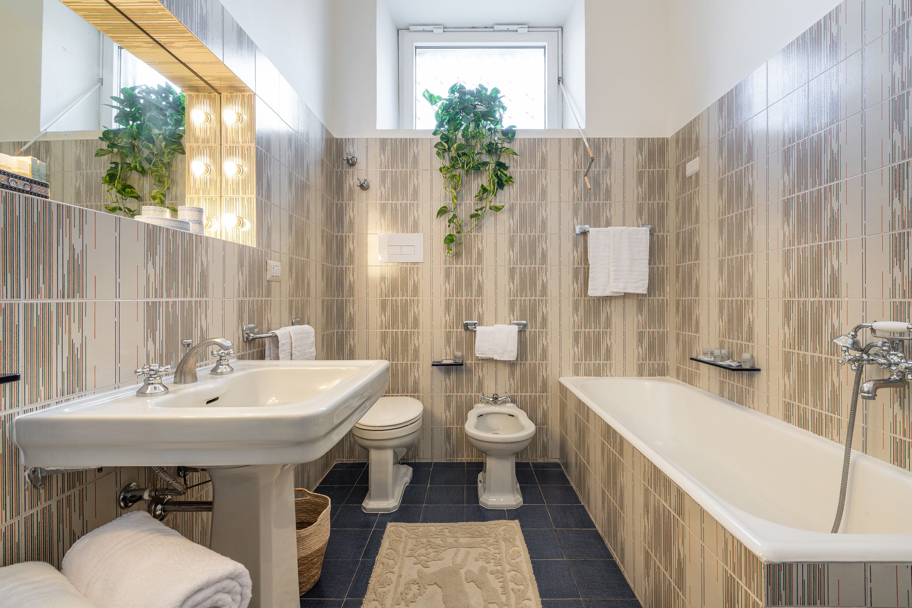 Un bagno moderno con un lavandino grande, due servizi igienici, un bidet e una vasca da bagno.