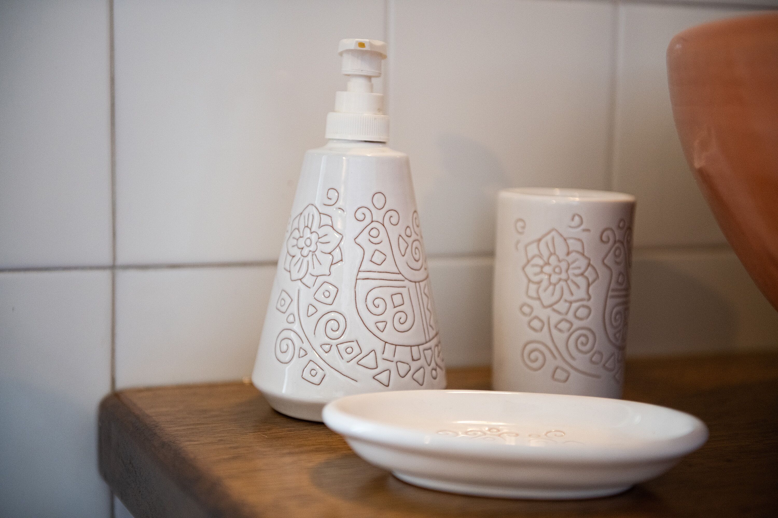 A bathroom with a wooden countertop, a soap dispenser, and a decorative mug.