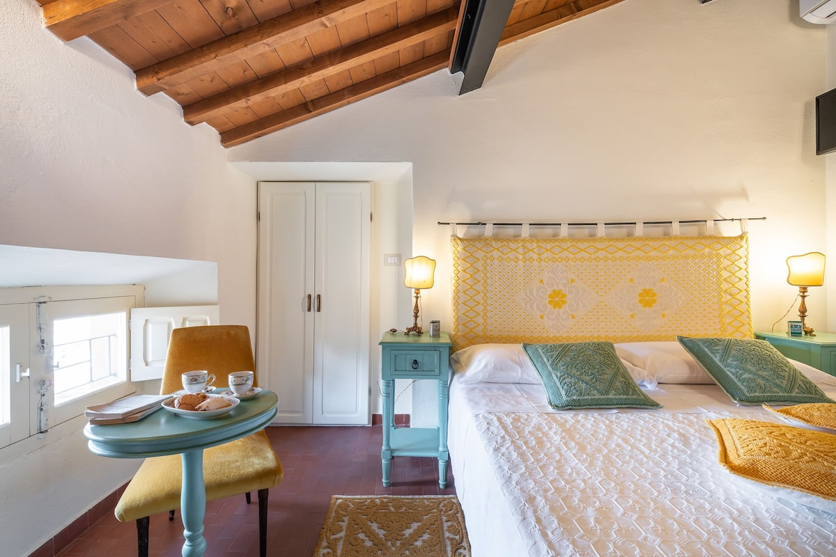 A bedroom with a bed, bedside tables, a chair, and a small table with a lamp.