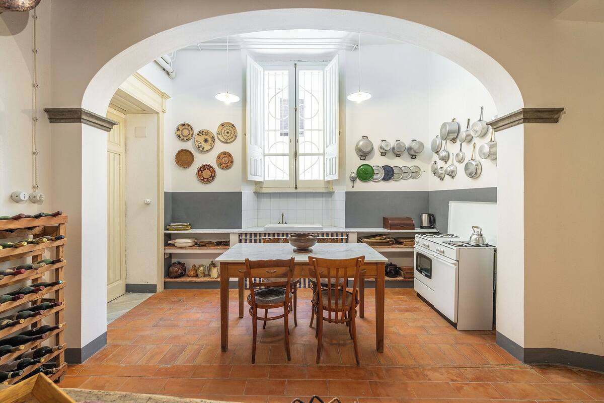 A kitchen with a dining table, chairs, a stove, and a window.