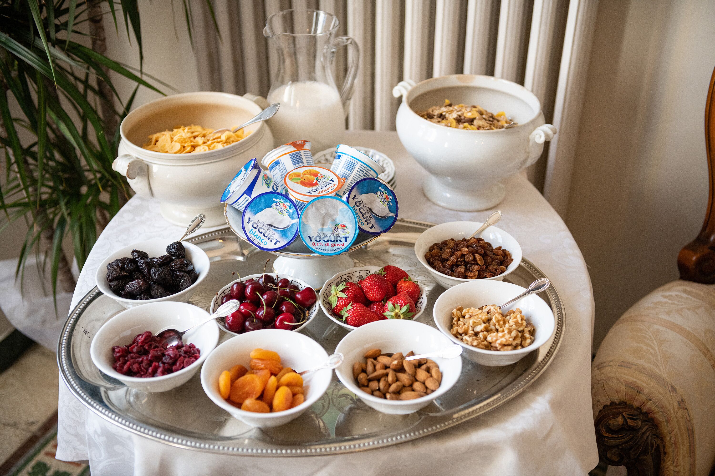 A breakfast table with various food items and a pitcher of milk.
