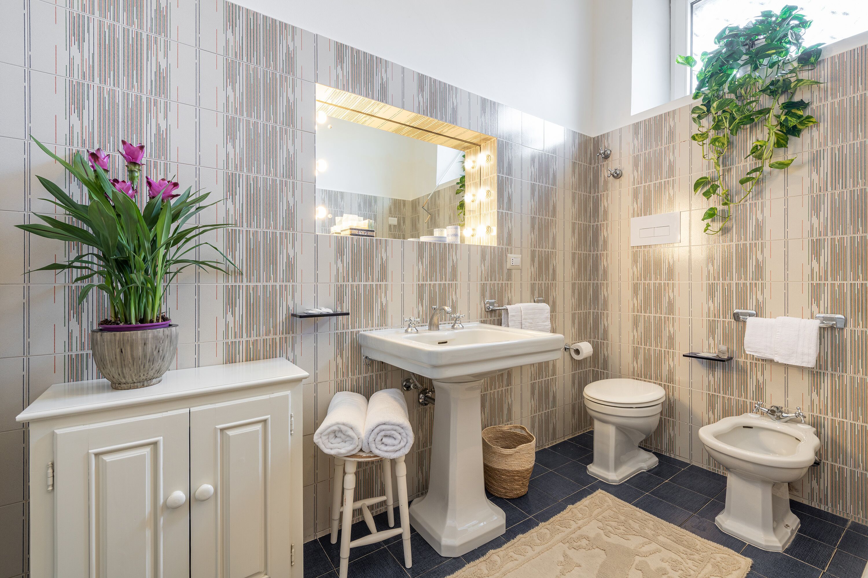 Une salle de bain équipée d’un lavabo sur colonne, de toilettes, d’un bidet et d’un meuble contenant des serviettes.