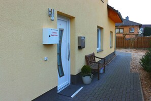 A building with a check-in box sign, a door, a bench, and a potted plant. - Penny Pension (Wolfsburg)