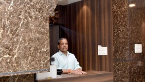 A reception desk with a marble finish, a wooden panel, and a clock on the wall. - Hotel Maple Inn (Patna)