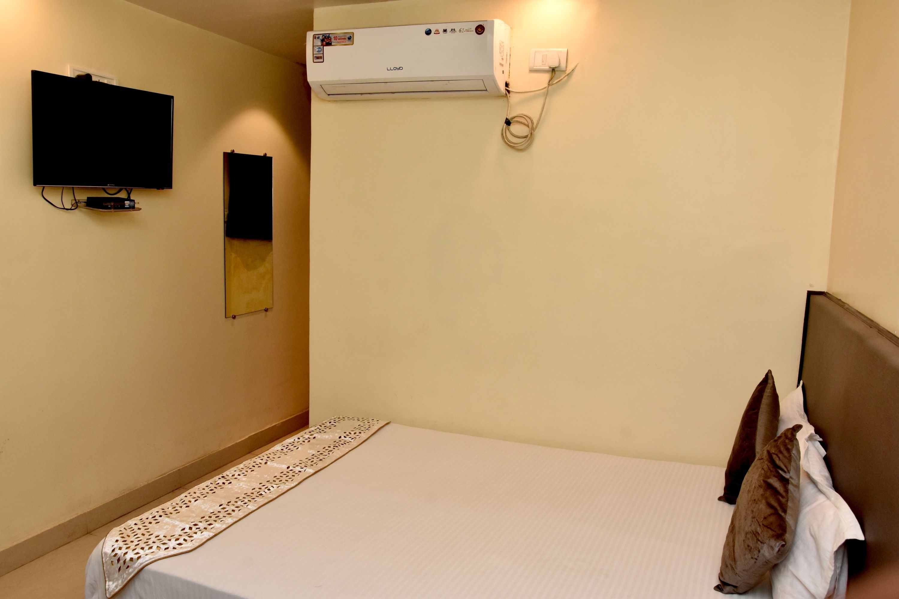 Habitación de hotel con cama, televisor de pantalla plana montado en la pared y aire acondicionado.