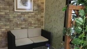 A room with a brick wall, a framed picture, a sofa, a small table, and a plant. - Hostal Restaurante Cuatro Caminos (Piedrabuena)