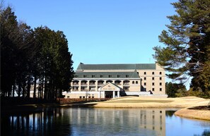 A large building with a green roof, a central entrance with a triangular pediment, and a reflection in the water in front. - Hotel Windsor (Nakatsugawa)