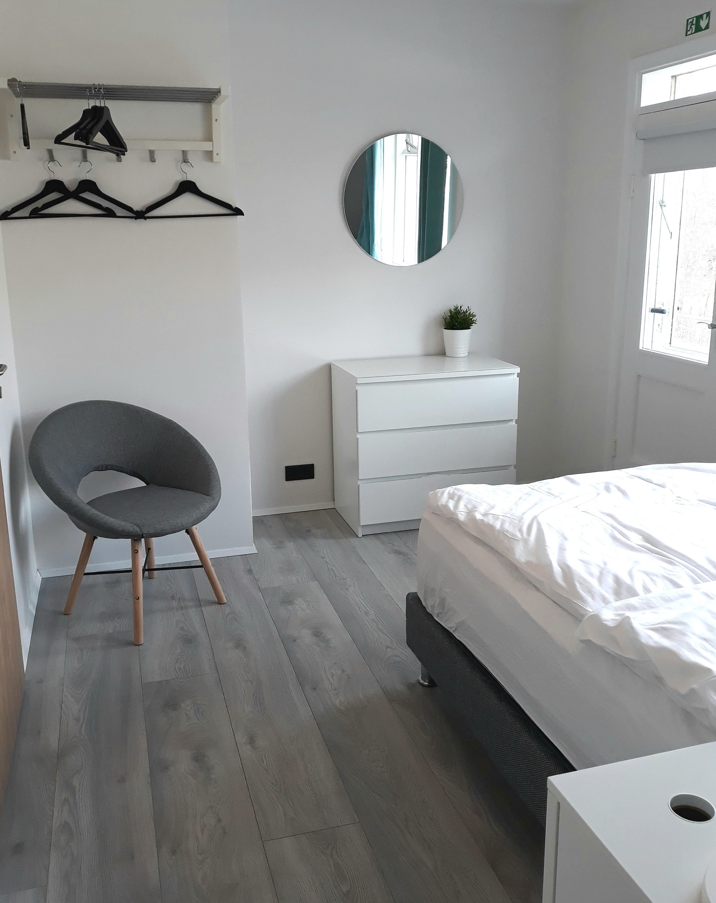 Un dormitorio con cama, cómoda, silla y espejo.