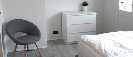 Un dormitorio con cama, cómoda, silla y espejo.