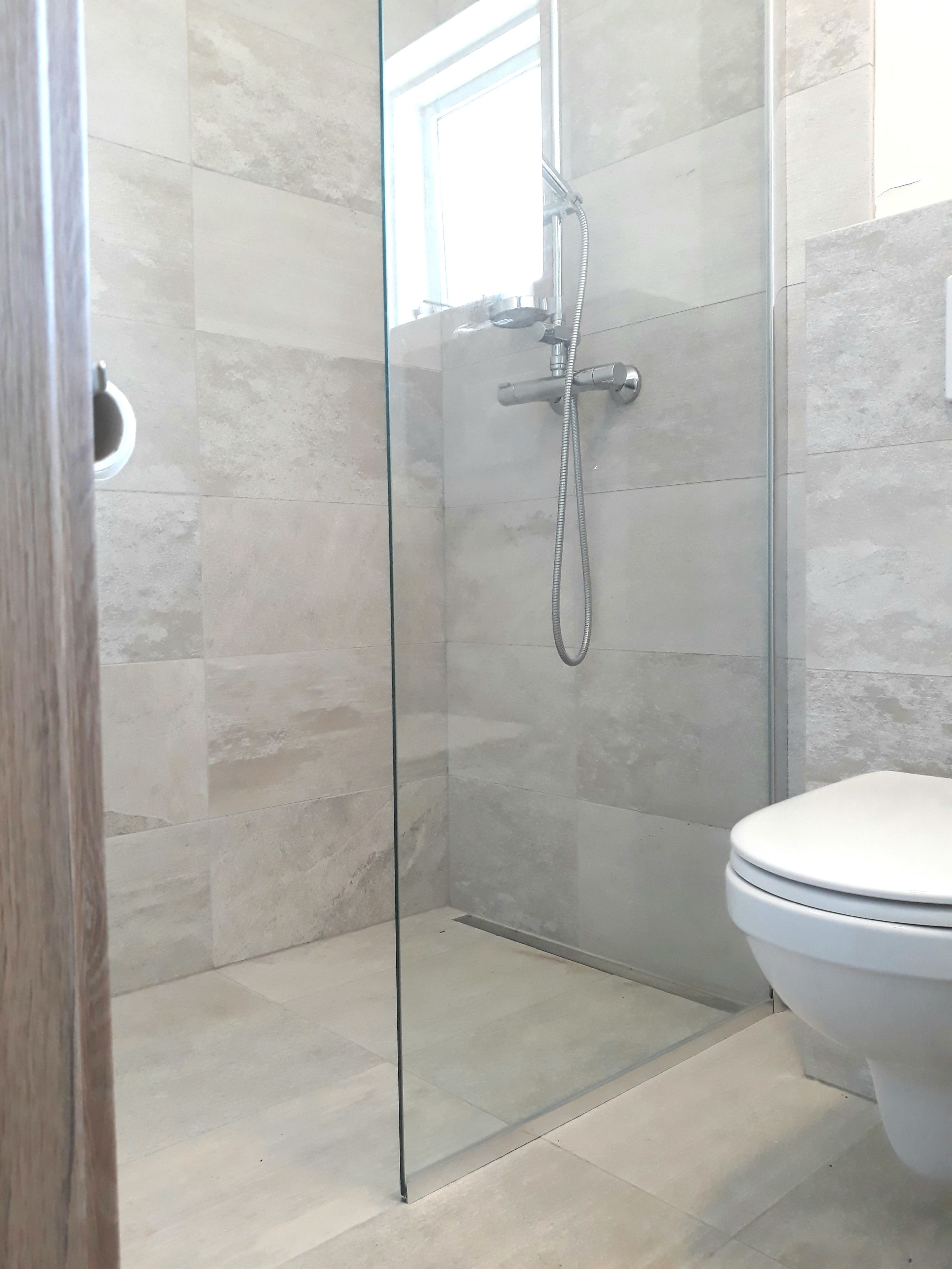 Een douchecabine met glazen wanden, met een wit toilet ernaast.
