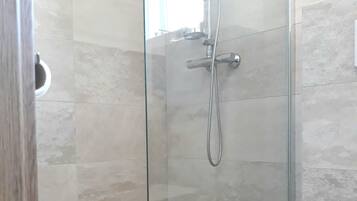 Een douchecabine met glazen wanden, met een wit toilet ernaast.