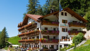 Ein mehrstöckiges Hotel mit Balkonen, die mit Blumen geschmückt sind, an einem Hang gelegen.