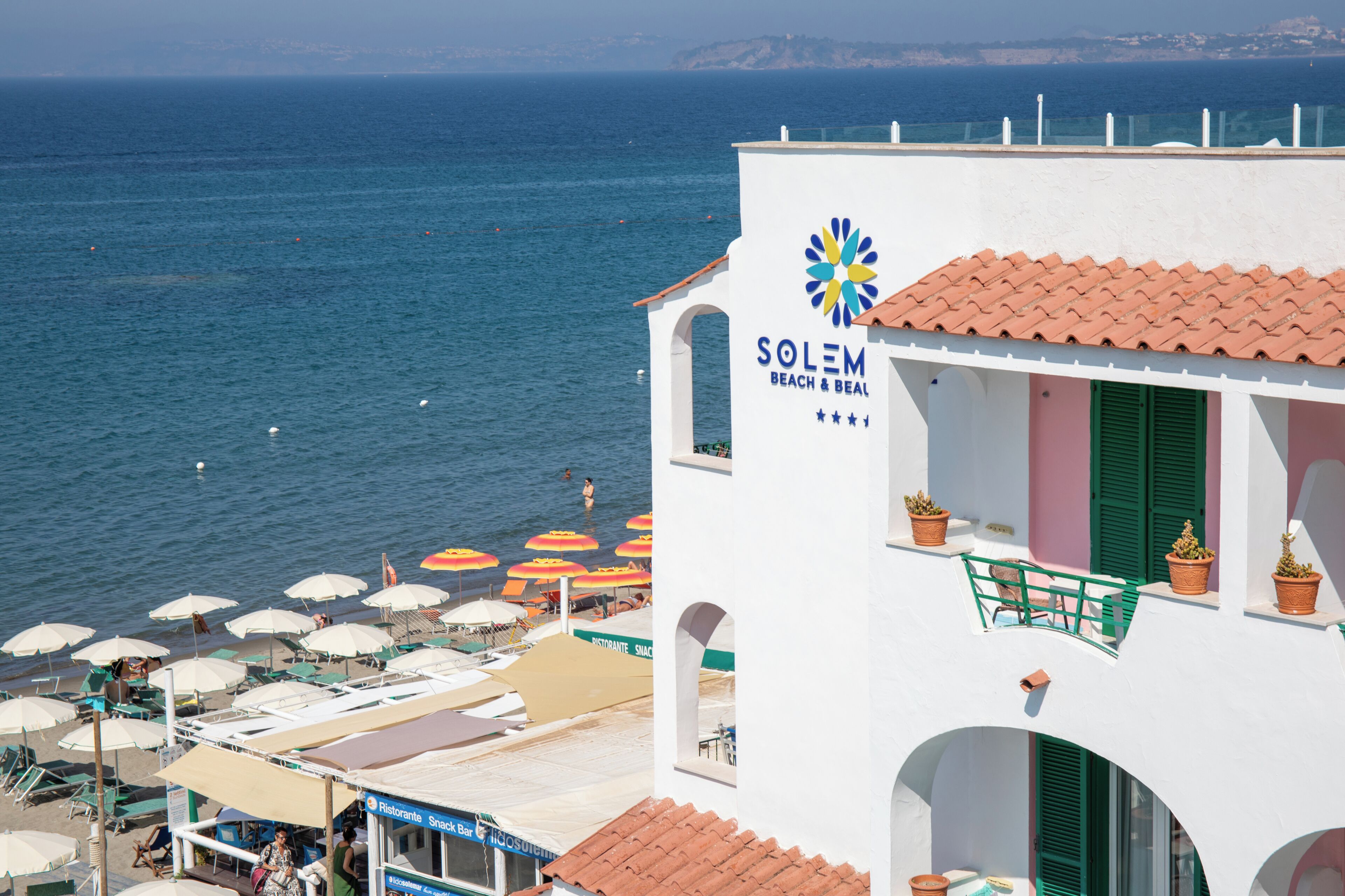 Un bâtiment blanc avec une enseigne indiquant « SOLEM BEACH & BEAL » et une vue sur la mer.