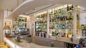 A bar area with shelves of various liquor bottles, a bar counter, and yellow bar stools. - Hotel Solemare Beach & Beauty SPA (Ischia)