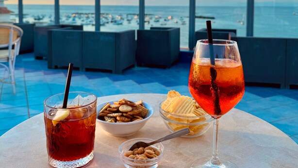 Two drinks, a bowl of nuts, and a bowl of ice cream on a table with a view of the sea. - Hotel Solemare Beach & Beauty SPA (Ischia)