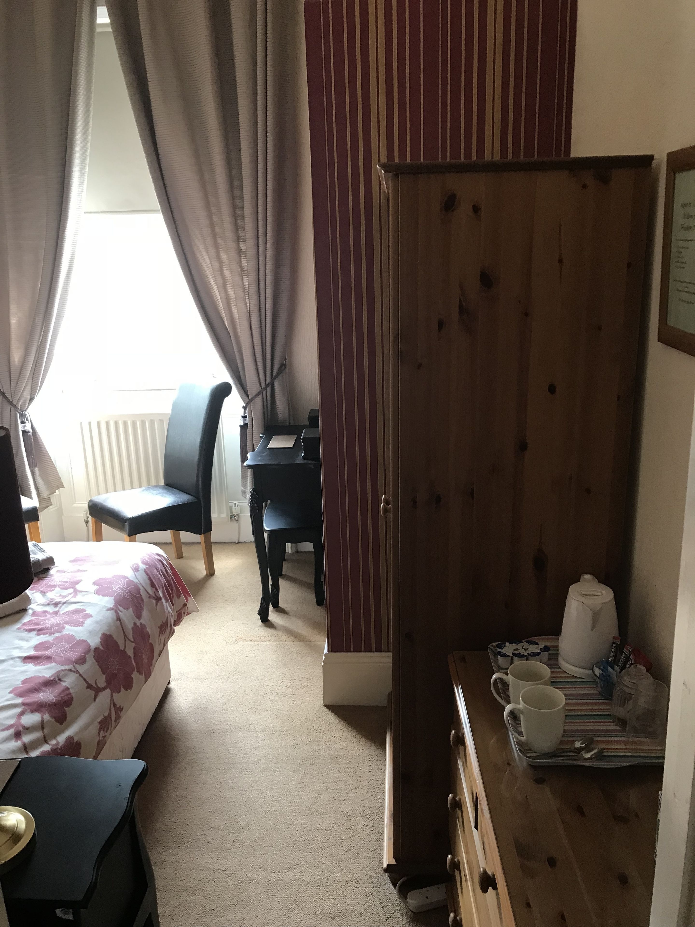 A bedroom with a bed, a desk, a chair, and a wardrobe.